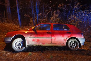 na zdjęciu czerwony samochodu osobowy w rowie