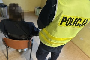 na zdjęciu policjant, a obok na krześle zatrzymana kobieta