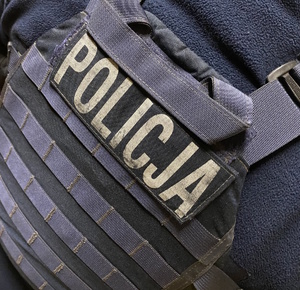 na zdjęciu fragment kamizelki z napisem policja