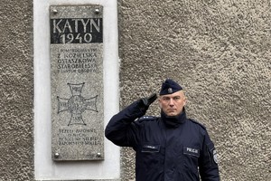 na zdjęciu policjant oddający honor pod pamiątkową tablicą