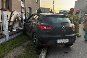 na zdjęciu samochód z uszkodzeniami przy ogrodzeniu posesji