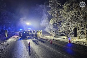Na drodze po zmroku pojazd na drodze obok niego strażacy obok w rowie inny rozbity pojazd
