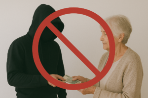 na zdjęciu zakapturzona osoba odbiera od seniorki pieniądze