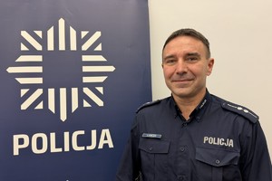 na zdjęciu dzielnicowy kowalczyk przy banerze z napisem policja