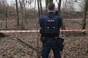 na zdjęciu policjant przy ogrodzonym terenie taśmą