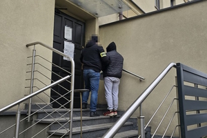 na zdjęciu policjant z zatrzymanym na schodach