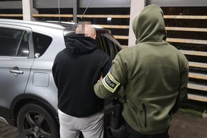 na zdjęciu policjant z zatrzymanym przy radiowozie