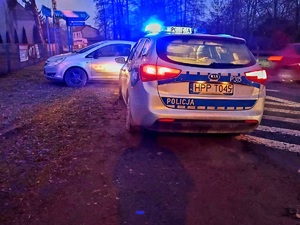 na zdjęciu stojący na poboczu radiowóz i przed nim widoczny jest zaparkowany opel