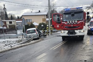 na zdjęciu rozbity samochód osobowy na jezdni, obok wóz strażacki
