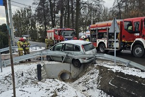 na zdjęciu rozbity samochód osobowy na jezdni, obok wóz strażacki