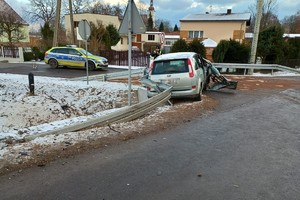 na zdjęciu rozbity samochód na jezdni, obok policjant i radiowóz policyjny
