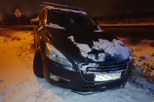 na zdjęciu czarny samochód po zmroku częściowo w rowie