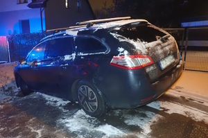 na zdjęciu czarny samochód po zmroku częściowo w rowie