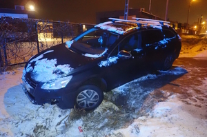 na zdjęciu czarny samochód po zmroku częściowo w rowie