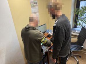 na zdjęciu technik kryminalistyki w trakcie pobierania odcisków palców od zatrzymanego