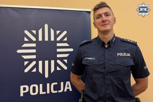 na zdjęciu dzielnicowy Kampa przy banerze z napisem Policja