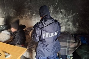 na zdjęciu policjantka w pomieszczeniu i osoba siedząca na łóżku
