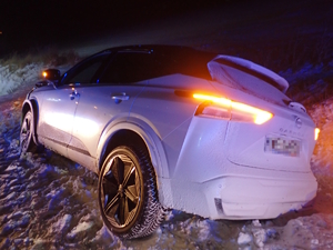 na zdjęciu biały samochód osobowy w przydrożnym, ośnieżonym rowie, po zmroku