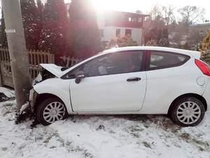na zdjęciu samochód z uszkodzeniami wbity w słup i ogrodzenie