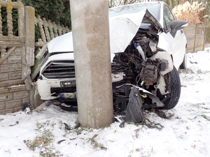 na zdjęciu samochód z uszkodzeniami wbity w słup i ogrodzenie