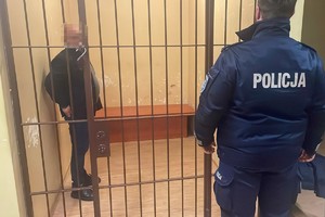 na zdjęciu policjant przed celą, w której stoi mężczyzna