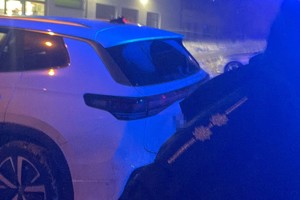 na zdjęciu fragment munduru policjanta oraz samochód