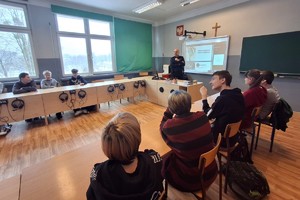 na zdjęciu dzielnicowy z młodzieżą w sali szkolnej