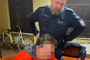 na zdjęciu dzielnicowy, obok którego siedzi zatrzymany w trakcie podpisywania dokumentów