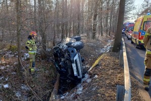 na zdjęciu samochód w rowie, obok strażak i wozy służby