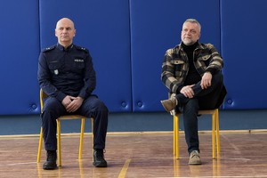 na zdjęciu aktor i policjanta na krzesłach w sali
