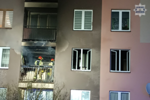 Na zdjęciu fragment budynku wielorodzinnego na którym widać strażaków na balkonie spalonego mieszkania