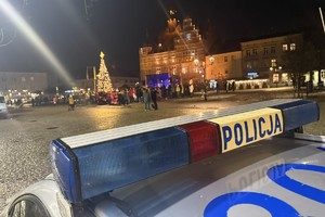 na zdjęciu fragment radiowozu i płyta tarnogórskiego rynku, na której stoją osoby