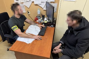 na zdjęciu policjant przy biurku z zatrzymanym w kajdankach