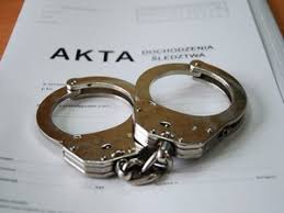 na zdjęciu kajdanki leżące na aktach