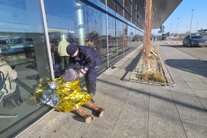 na zdjęciu policjant okrywa kocem termicznym osobę siedzącą na ziemi