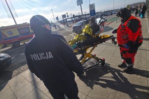 na zdjęciu osoba na noszach, obok policjant i ratownik medyczny