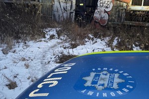na zdjęciu fragment radiowozu i policjant sprawdzający pustostan