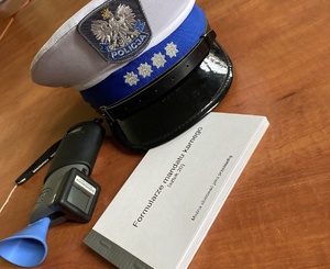 na zdjęciu urządzenie do badania trzeźwości, policyjna czapka i bloczek mandatów karnych