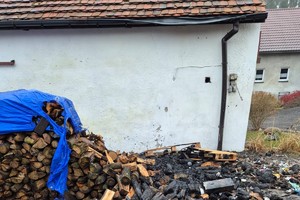 na zdjęciu nadpalone drewno opałowe przy budynku