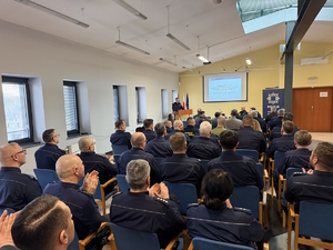 na zdjęciu sala, w której na krzesłach siedzą zebrani przed ekranem