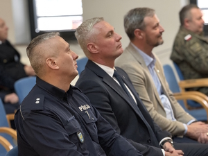 na zdjęciu siedzący na widowni policjant i goście
