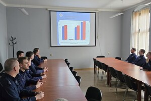 na zdjęciu policjanci za stołami, na ekranie prezentacja