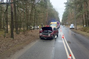 na zdjęciu rozbity pojazd na jezdni, za nim karetka pogotowia, radiowóz i wozy strażackie oraz osoby i ratownicy