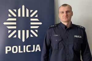 kierownika Kordas przy banerze z napisem policja