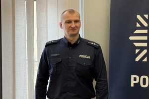 na zdjęciu policjant przy banerze w sali