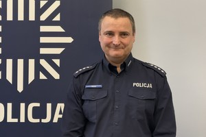na zdjęciu policjant przy banerze w sali
