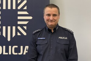 na zdjęciu policjant przy banerze w sali