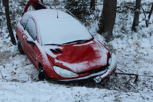 na zdjęciu czerwony samochód w rowie