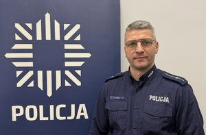 na zdjęciu dzielnicowy przy banerze z napisem policja