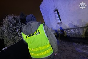 na zdjęciu policjant w odblaskowej kamizelce przy budynku